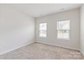 Bright bedroom featuring neutral carpet, two windows, and electrical outlets at 10241 Black Locust Ln, Charlotte, NC 28215