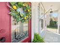 Up-close view of a red front door with a decorative lemon wreath and glass panel detailing at 1034 Currituck Way, York, SC 29745