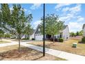 A street view of a well-maintained one-story home with lush trees and manicured landscaping at 1774 Slippery Rock Ln, Monroe, NC 28112