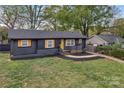 Charming, newly renovated home with black exterior, wood shutters, and a bright yellow door at 1814 Eastway Dr, Charlotte, NC 28205