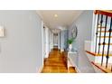 Hallway with hardwood floors, with mirror and plant, leading to rooms with ample natural light at 22970 Lake Tillery Rd, Albemarle, NC 28001