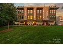 Beautiful townhome with well-manicured lawn and vibrant sunset reflecting in the windows at 327 Uptown West Dr, Charlotte, NC 28208