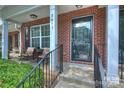 Welcoming brick front porch with seating area, wrought iron railing, and decorative glass front door with address at 8453 Big Creek Ct, Charlotte, NC 28105
