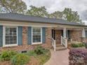 Inviting brick home featuring teal shutters, a front patio, manicured landscaping, and a walkway at 1340 Braeburn Rd, Charlotte, NC 28211