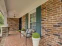 Inviting covered front porch featuring a bench, neutral pillows, potted plants, and a brick wall at 1340 Braeburn Rd, Charlotte, NC 28211