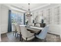 This spacious dining room features decorative wainscoting, an elegant chandelier and large windows at 13408 Chopin Ridge Rd, Huntersville, NC 28078