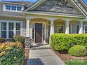 Inviting front porch with stone pillars, manicured bushes, and a dark wood front door with sidelights at 2030 Gloucester St, Weddington, NC 28104