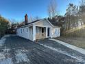 Single story home with a gravel driveway, chimney, and covered porch at 2300 Olando St, Charlotte, NC 28206
