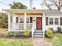 Inviting covered front porch with wood ceiling, stylish railings and a bright red front door at 2843 Cowles Rd, Charlotte, NC 28208