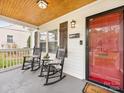 Cozy front porch with rocking chairs, a glass table, and a bright red front door at 2843 Cowles Rd, Charlotte, NC 28208