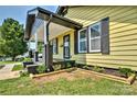 This home features a welcoming porch with gray trim, yellow siding, and professionally landscaped garden beds at 302 Griffith Rd, Monroe, NC 28112