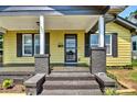 Charming yellow home with updated porch featuring brick stairs, gray trim, and black shutters at 302 Griffith Rd, Monroe, NC 28112