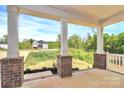 View from the covered front porch showcasing brick supports, landscaping, and a clear view of the neighborhood at 3204 Leah Elizabeth Ln, Monroe, NC 28110