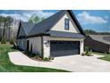 Side view of home featuring a spacious garage with black doors and a well-kept driveway at 4210 Holly Ne Cir, Conover, NC 28613