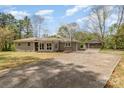 Spacious driveway leading to a charming one-story home with a detached carport and blossoming trees at 5323 Hilltop Cir, Charlotte, NC 28269