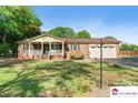 Inviting brick home boasts a cozy front porch, mature landscaping, and a two-car attached garage at 552 Odell School Rd, Concord, NC 28027
