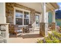 Charming front porch with stone supports, seating, and decorative wreath on the front door creating a welcoming entrance at 11144 Limehurst Pl, Charlotte, NC 28278