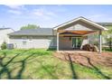 View of the backyard with covered patio, mature landscaping, and level lawn at 1838 Summit Ridge Ln, Kannapolis, NC 28083