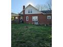 View of the backyard of a red brick home, featuring grassy area and exterior utilities at 307 Gold Hill Ave, Rockwell, NC 28138