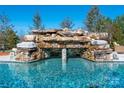 Stunning pool features a captivating rock waterfall, creating a serene and luxurious backyard oasis at 9610 Pensive Ln, Waxhaw, NC 28173