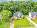 Aerial shot of brick home featuring a large manicured lawn and a driveway surrounded by lush greenery at 1102 High Brook Dr, Waxhaw, NC 28173