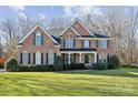 Traditional brick home boasts manicured landscaping, symmetrical windows, and a covered front porch at 1102 High Brook Dr, Waxhaw, NC 28173