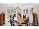 Well-lit dining room with a rustic wood table, seating for six, modern chandelier, and large window at 11615 Hidden Grove Trl, Charlotte, NC 28215