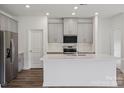 Bright kitchen showcasing gray cabinets, stainless steel appliances, a white countertop island, and elegant backsplash tiles at 1234 Morehead Dr, Salisbury, NC 28144