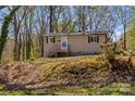 Charming tan home with black trim and front porch nestled among trees on a sunny day at 216 E Georgia Ave, Bessemer City, NC 28016