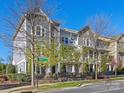 Attractive townhouse exterior with street view, manicured landscaping, black metal fence, and street sign that reads 