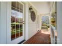 Inviting covered porch featuring brick flooring, white railings, and decorative wall art, offering a cozy outdoor space at 3717 Bodenham Ct, Charlotte, NC 28215