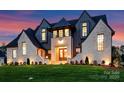 Striking exterior elevation featuring dramatic lighting, manicured lawn, and lush landscaping at 406 Sugar Maple Ln, Weddington, NC 28104