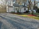 Landscaped yard with manicured beds, a gravel driveway, and a charming home with a classic design at 609 Mccarten St, Monroe, NC 28112