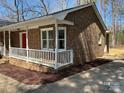 Brick house featuring a cozy porch and red door with new landscaping at 10607 Wood Meadow Dr, Charlotte, NC 28227