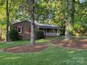A quaint brick home is nestled amongst mature trees and lush landscaping at 10607 Wood Meadow Dr, Charlotte, NC 28227