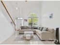 Inviting living room featuring a soaring ceiling, staircase, and a modern sectional sofa with decorative pillows at 13521 Michael Lynn Rd, Charlotte, NC 28278