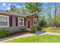 Inviting front entrance with a covered porch, red door, and well-maintained landscaping with mature trees at 1725 Bristol Rd, Statesville, NC 28677