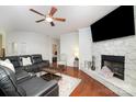 Open living room with stone fireplace, dark floors, ceiling fan and plush leather seating at 306 Nance Rd, Charlotte, NC 28214