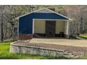 Attached carport featuring a brick accent wall, concrete floor, and access to the backyard and upper level at 923 Wyke Rd, Shelby, NC 28150