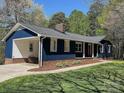 Rear view showcasing dark blue siding, brick foundation, and attached carport nestled within a serene wooded area at 923 Wyke Rd, Shelby, NC 28150
