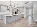 Spacious kitchen features an island with pendant lighting, stainless appliances and light gray cabinetry at 9934 Cask Way, Huntersville, NC 28078