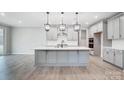 New kitchen features an island with pendant lighting, stainless appliances and light gray cabinets and flooring at 9934 Cask Way, Huntersville, NC 28078