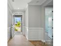 Bright foyer with wood floors, white wainscoting and stone front entrance in view at 9957 Cask Way, Huntersville, NC 28078