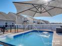 Inviting backyard pool with fountain features and an umbrella, perfect for summer relaxation and entertainment at 12848 Mustang Dr, Midland, NC 28107