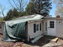 Close-up view of the front of a run-down one-story home, covered with a blue tarp and awaiting restoration at 1407 Birch St, Kannapolis, NC 28081