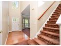Bright foyer with hardwood floors, staircase with carpet, and view into the large sunny living room at 2514 Waters Vista Cir, Charlotte, NC 28213