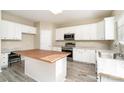 Eat-in kitchen with white cabinets, stainless appliances, butcher block island, and wood-look tile floors at 2514 Waters Vista Cir, Charlotte, NC 28213