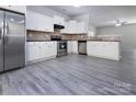 Modern kitchen featuring stainless steel appliances, granite countertops, white cabinets, and gray wood floors at 3308 Lemongrass Ln, Charlotte, NC 28214