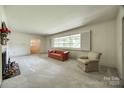 Bright living room featuring neutral carpet, large windows with shutters, and ample natural light at 3330 Foxcroft Rd, Charlotte, NC 28211