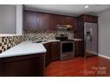Modern kitchen featuring stainless steel appliances, granite countertops, and dark wood cabinets at 4548 Antelope Ln, Charlotte, NC 28269